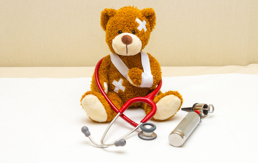 Brown teddy bear with bandages and broken hand in pediatrician's office